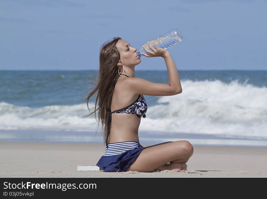 Woman drinking water in the beach