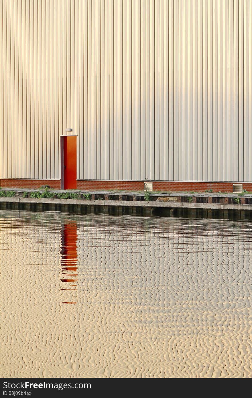 It shows a red door in front a stream of water. It shows a red door in front a stream of water