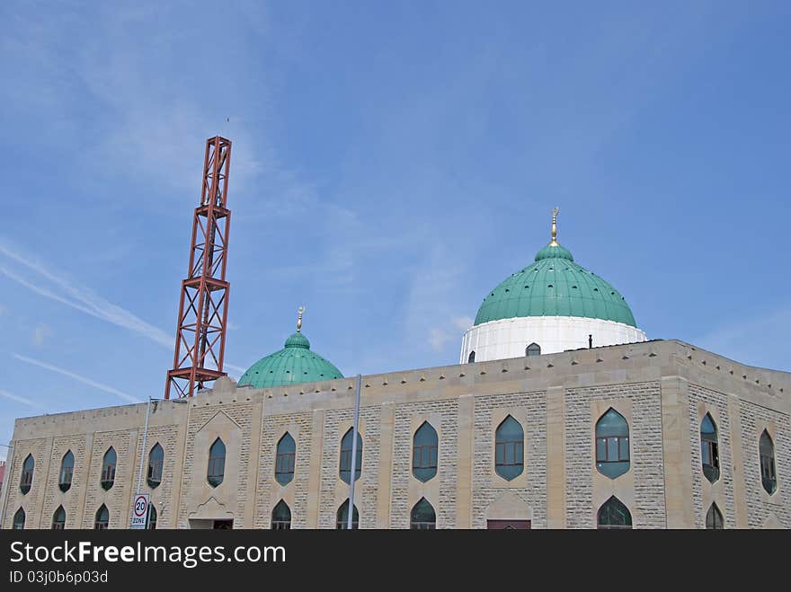 The Green Domes and Minaret of a modern Mosque in a mill town in West Yorkshire under a blue sky. The Green Domes and Minaret of a modern Mosque in a mill town in West Yorkshire under a blue sky