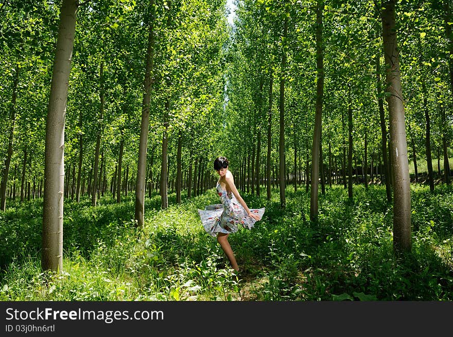 A woman dancing between trees wearing a dress. A woman dancing between trees wearing a dress