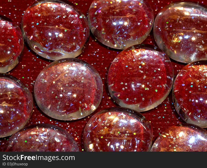 Glass craft pebbles on a sparkle red background. Glass craft pebbles on a sparkle red background.