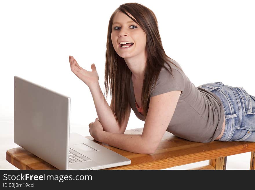 A teen laying on a bench working on her laptop. A teen laying on a bench working on her laptop.