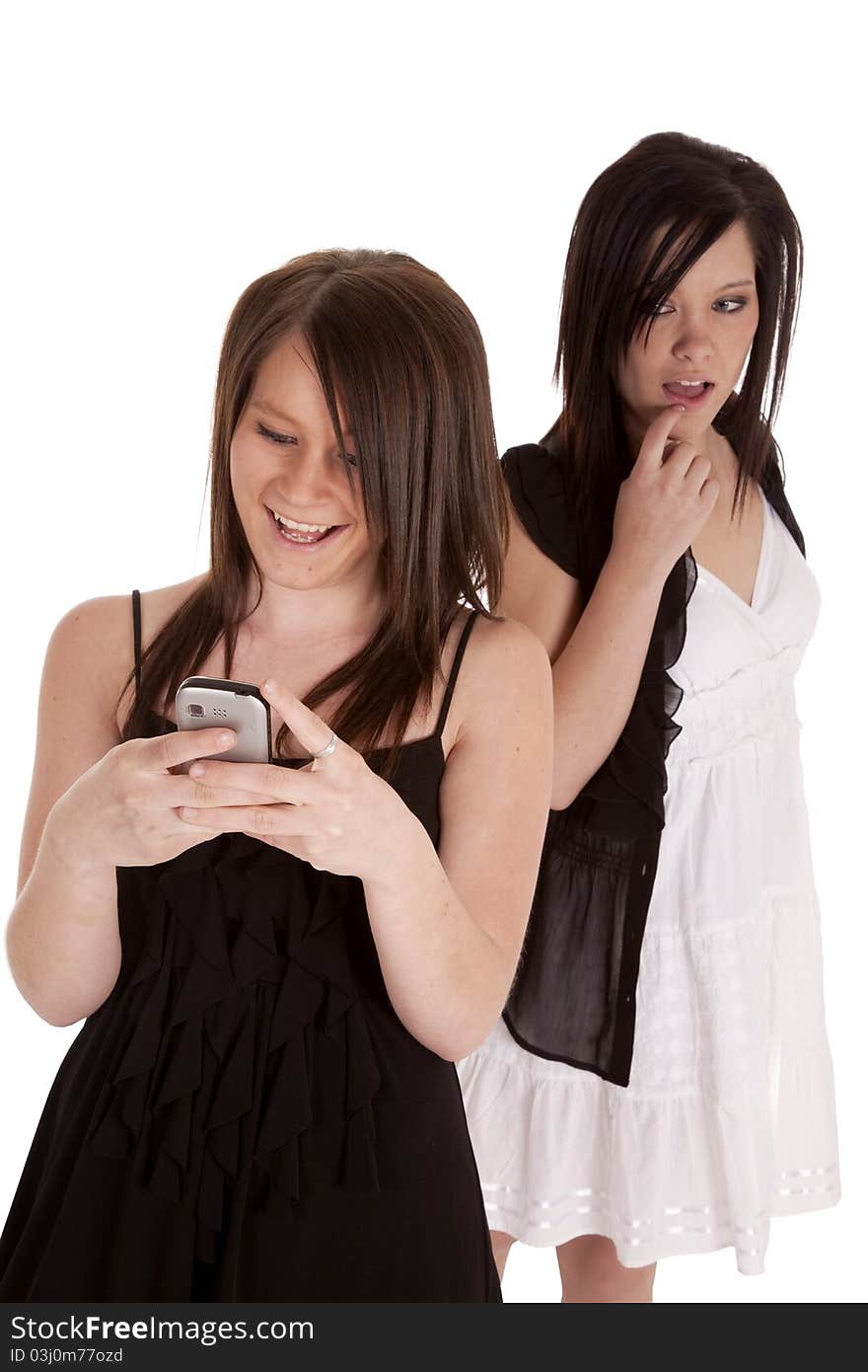 A teen girl looking over a shoulder while her friend is texting and enjoying what her friend is texting. A teen girl looking over a shoulder while her friend is texting and enjoying what her friend is texting.