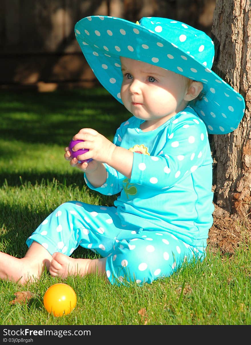 Toddler sitting on grass playing with colored ball