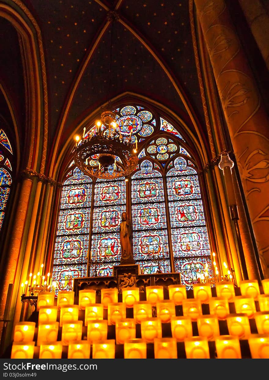 Candles in front of a stained window at Notre Dame Cathedral in Paris, France. Candles in front of a stained window at Notre Dame Cathedral in Paris, France.