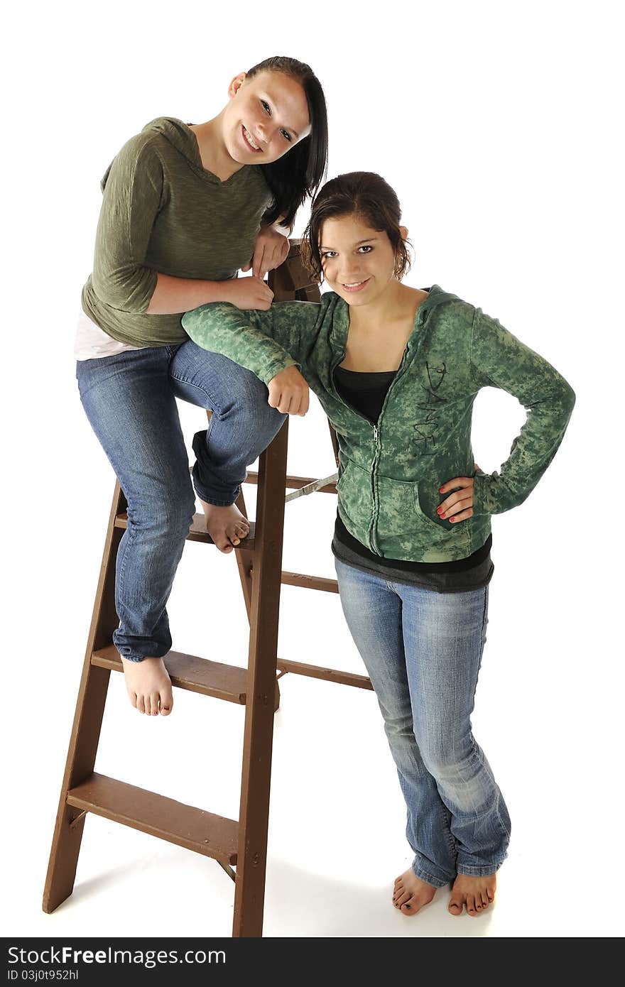 Portrait of two beautiful young teens in casual clothes posed with an old ladder. Portrait of two beautiful young teens in casual clothes posed with an old ladder.