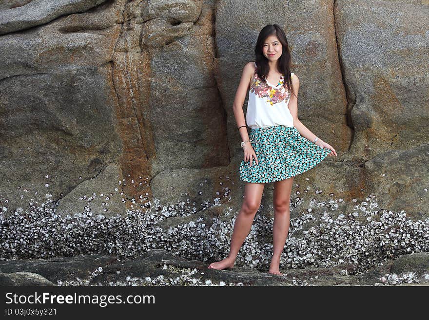 Beautiful young woman posing on stones near sea