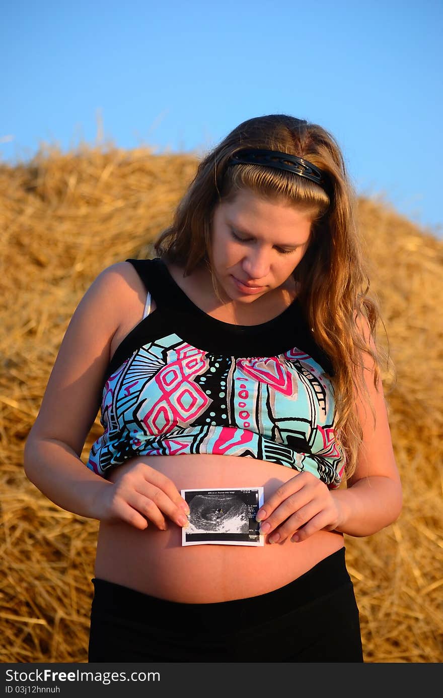 The pregnant girl on a mow with a picture. The pregnant girl on a mow with a picture