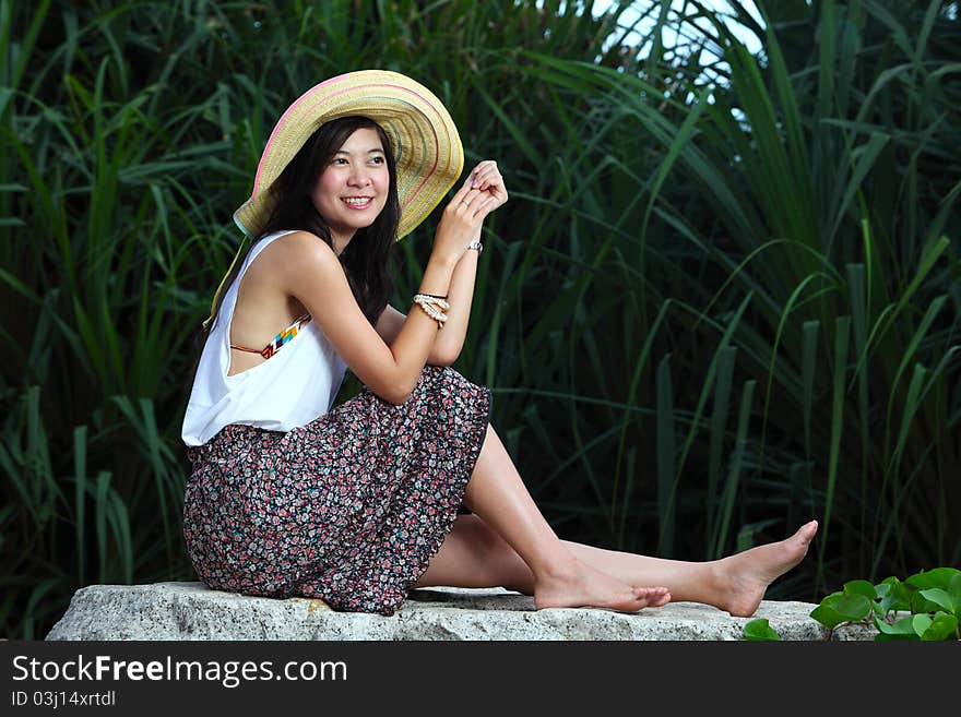 Beautiful woman on stone near sea