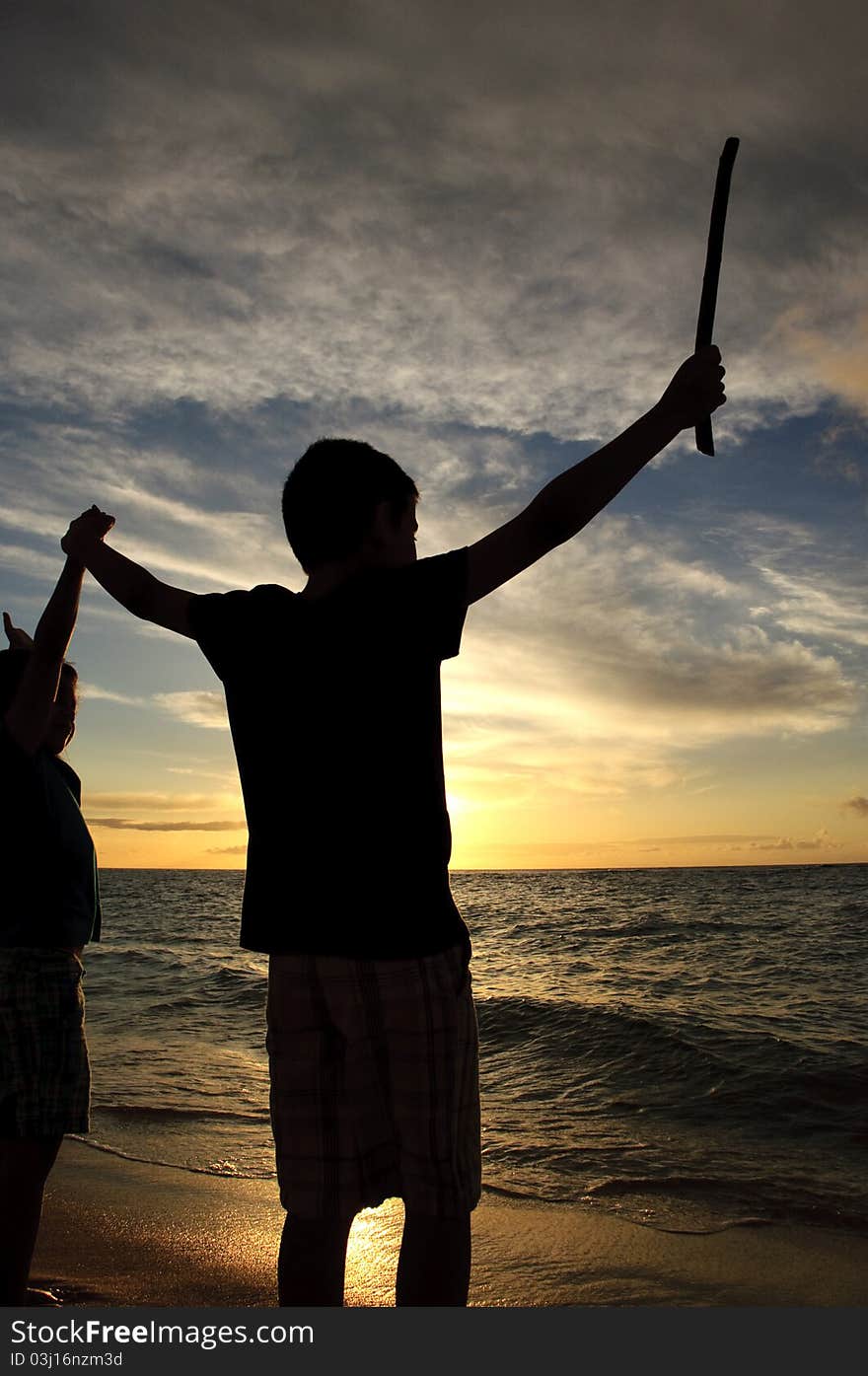 A brother and sister as they watch the sun setting over the Pacific Ocean on the North shore of Oahu in Hawaii. A brother and sister as they watch the sun setting over the Pacific Ocean on the North shore of Oahu in Hawaii.