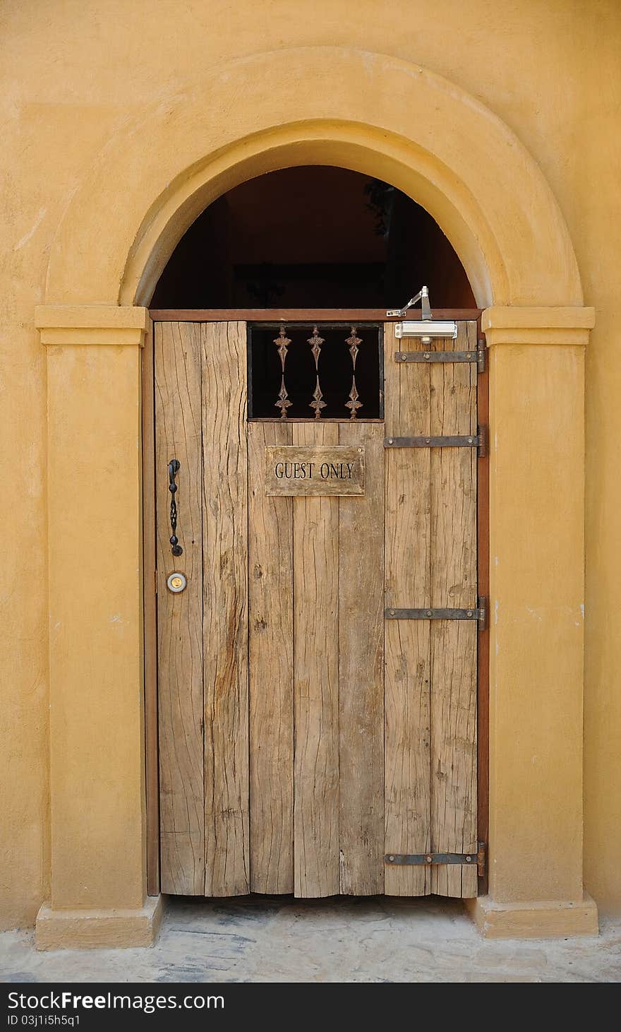 An old wooden door with yellow arch and wall