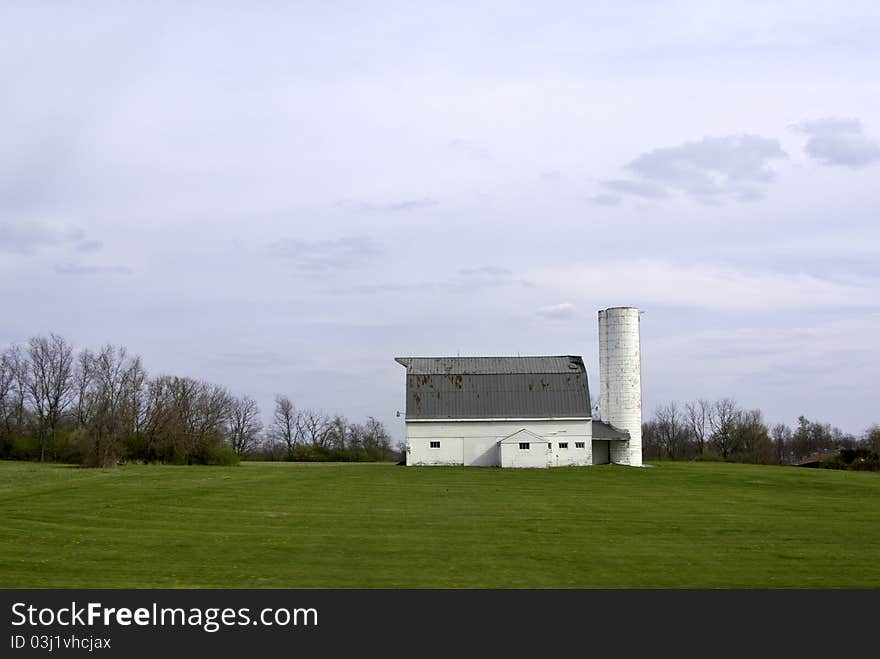 A view of a typical farm with rolling lawns and trees and clouds in the sky. A view of a typical farm with rolling lawns and trees and clouds in the sky.