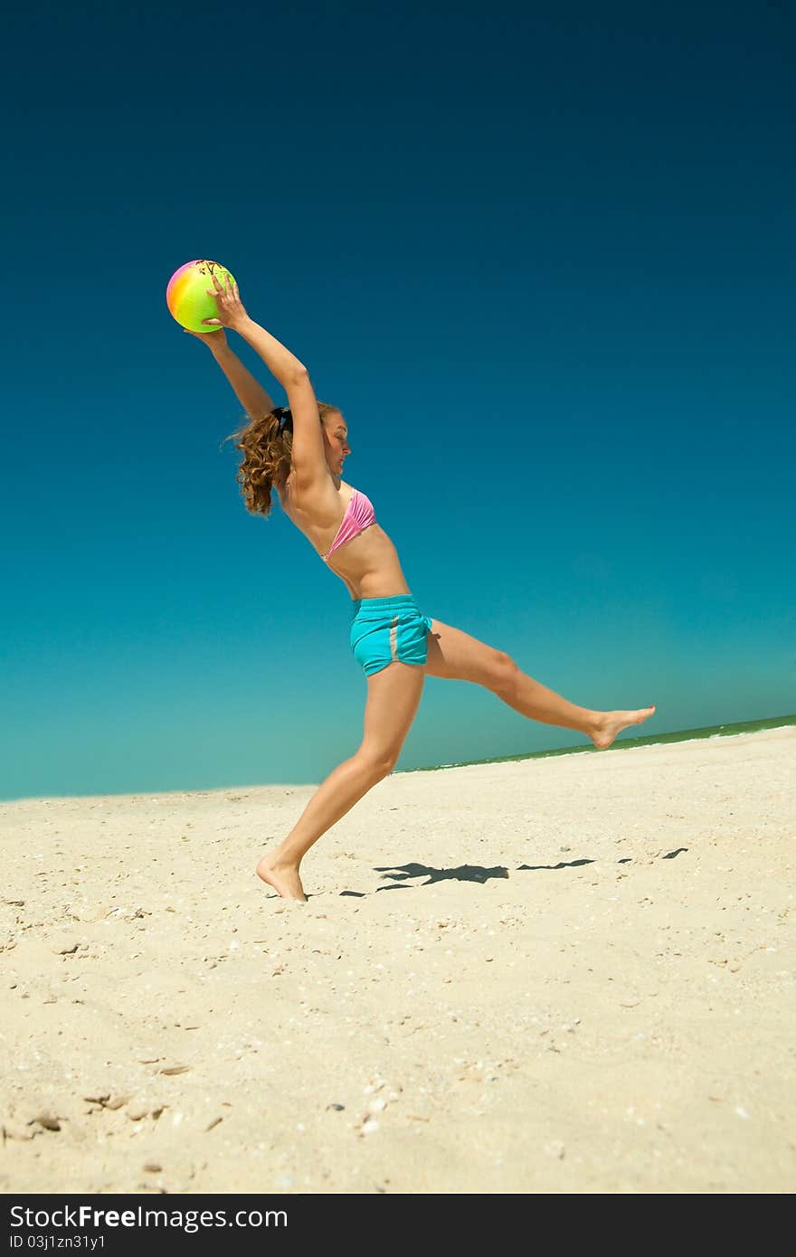 The ecstatic young girl playing volleyball at the beach