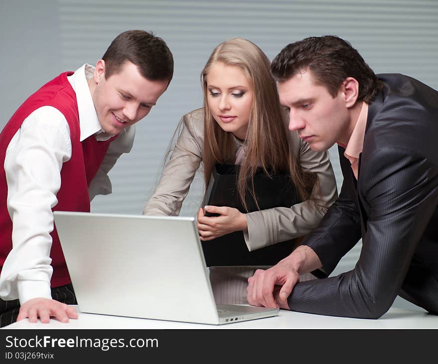 Two men and woman working with a computer in the office