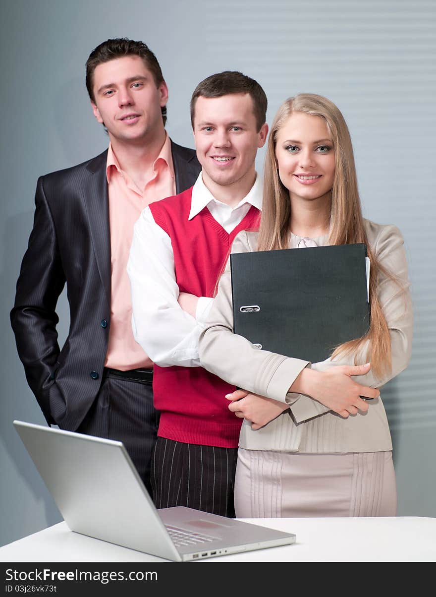 Two men and woman working with a computer