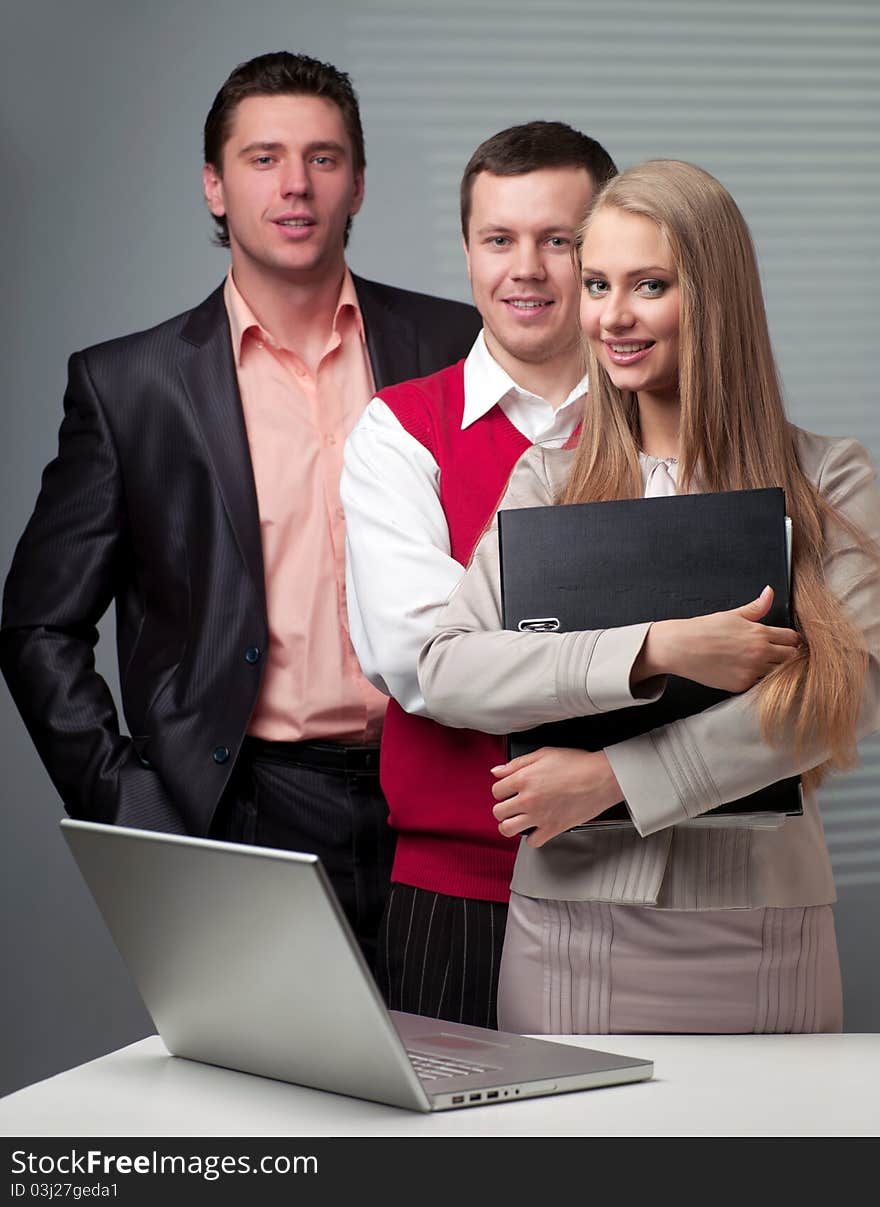 Two men and woman working with a computer