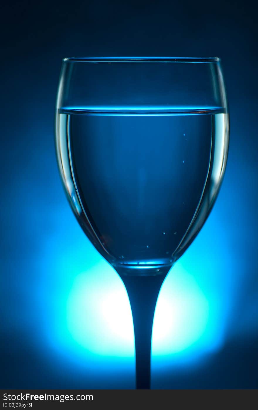 Close up shot of a glass with liquid over a blue lit background. Close up shot of a glass with liquid over a blue lit background