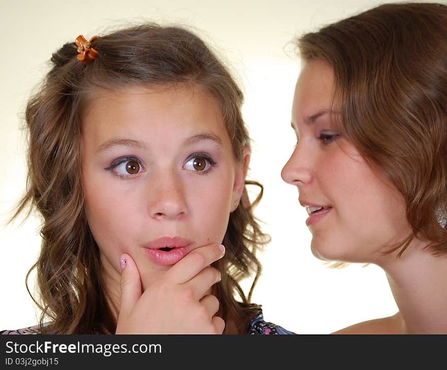 Two happy young girlfriends talking, gossips in secret