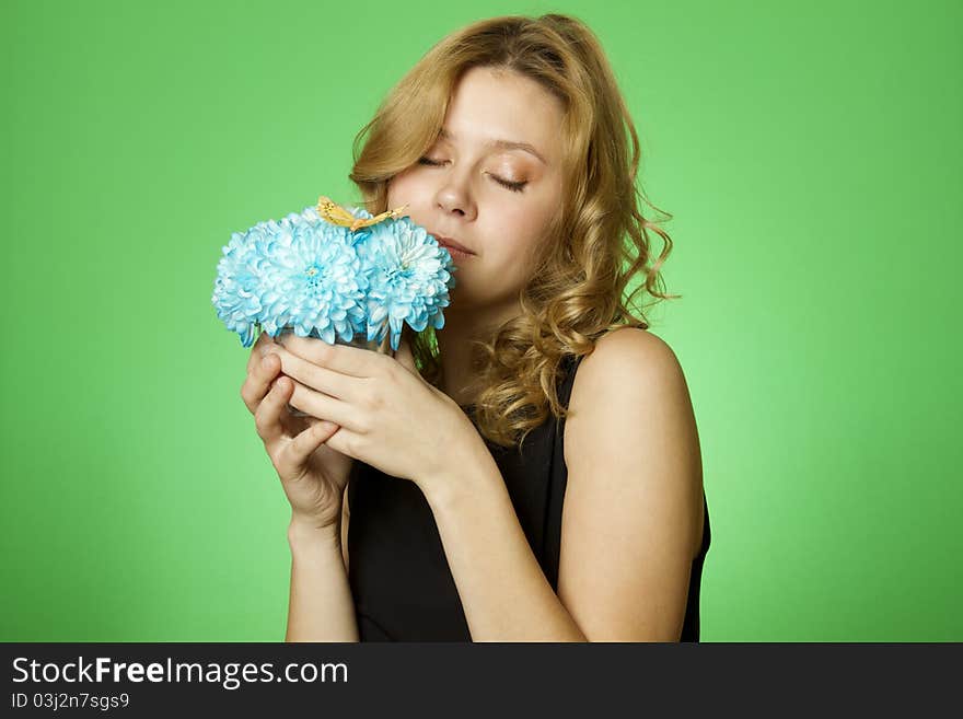 Close-up of an attractive young woman holding a gift bouquet of blue chrysanthemums sits on colors yellow butterfly. Close-up of an attractive young woman holding a gift bouquet of blue chrysanthemums sits on colors yellow butterfly