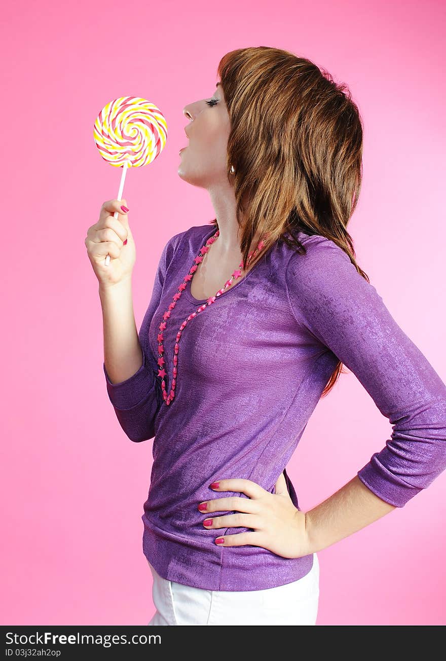 Portrait of girl with lollipop on pink background