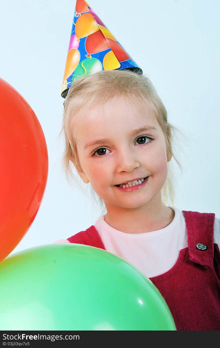 Beautiful little girl with birthday hat play with balloons