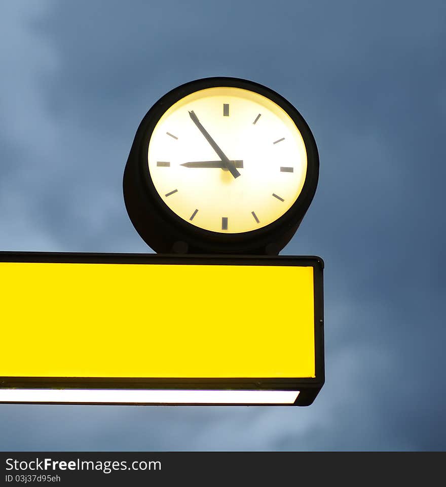 Empty signboard and clock over blue sky background