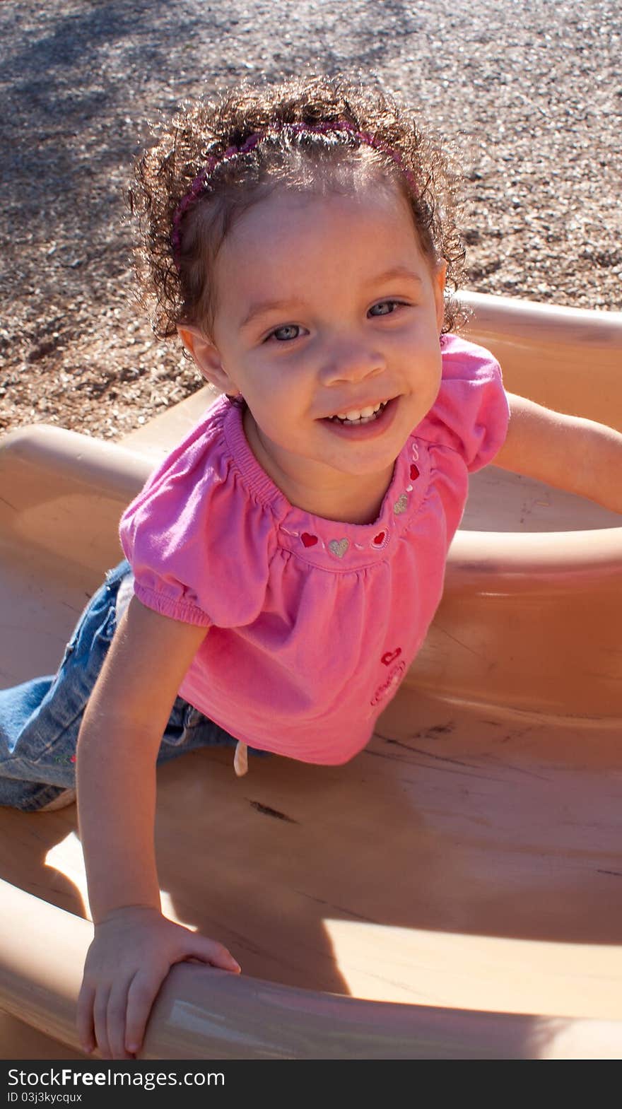 A happy little girl at the park playing on the slide. A happy little girl at the park playing on the slide