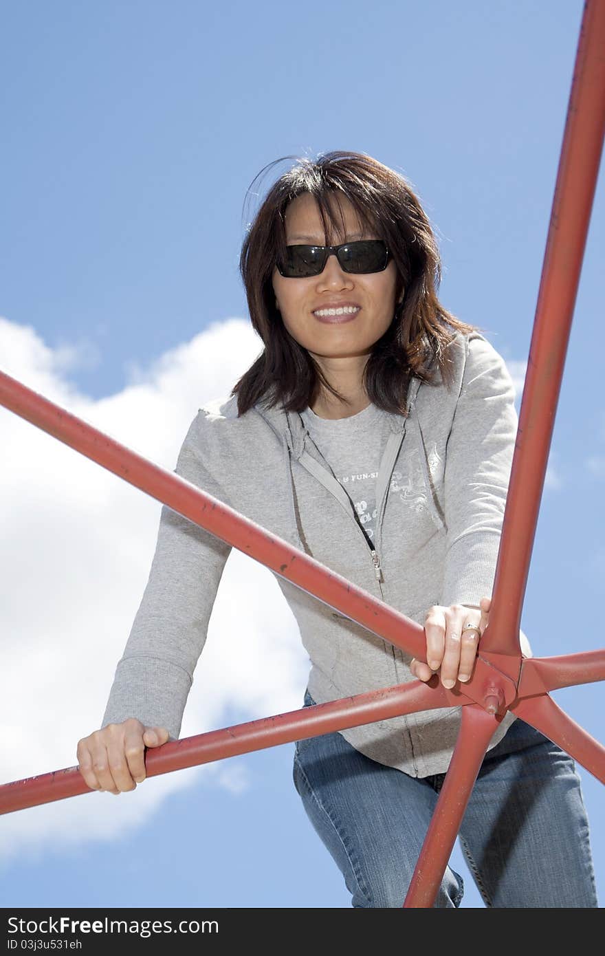 Woman leans on playground bars.