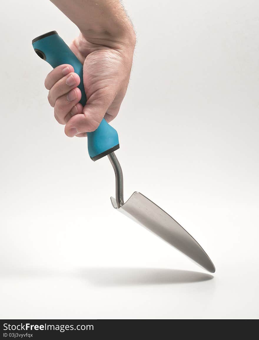 Hand using a garden trowel against white background