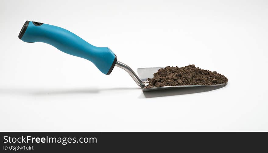 Garden trowel filled with dirt against isolated white background. Garden trowel filled with dirt against isolated white background