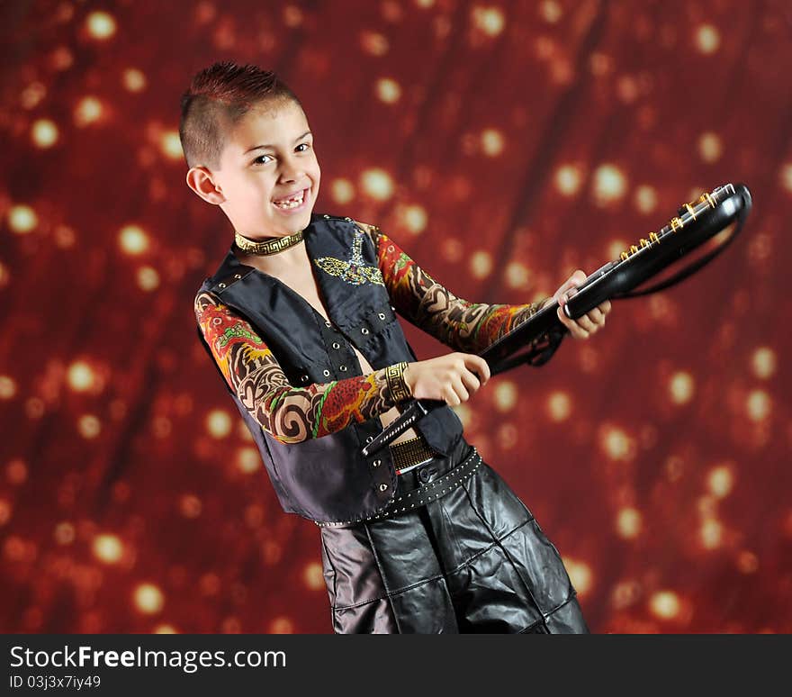 A happy elementary rock star weilding his guitar before a light-studded curtain. Motion blur on hands and guitar. A happy elementary rock star weilding his guitar before a light-studded curtain. Motion blur on hands and guitar.