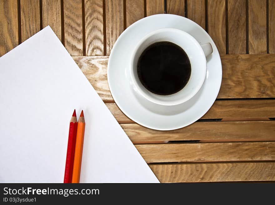 Paper blank Sheet, color pencil and a cup of coffee on a wooden table.