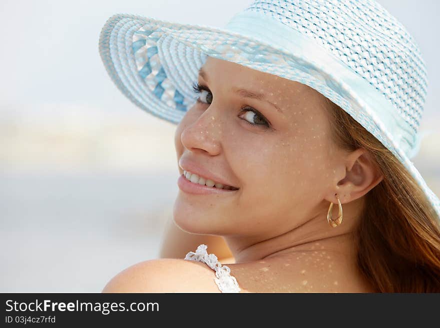 Beautiful happy young woman in straw hat smiling and looking over shoulders on the beach. Horizontal shape, copy space. Beautiful happy young woman in straw hat smiling and looking over shoulders on the beach. Horizontal shape, copy space