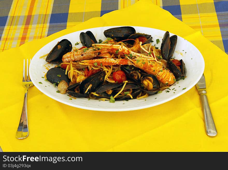 Spaghetti with sea food and tomato of the table prepared with yellow cloth