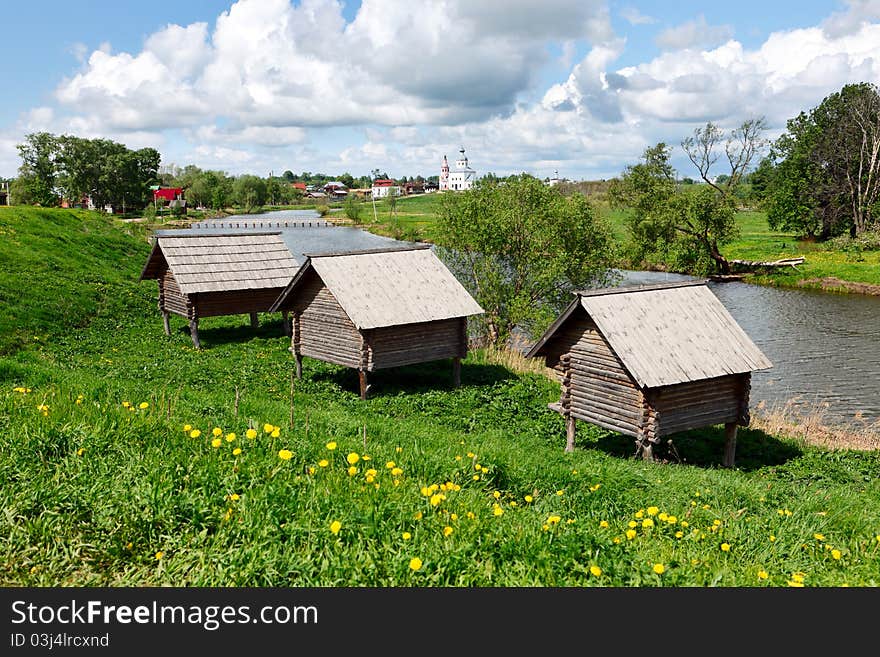 Wooden Houses At A River Bank.