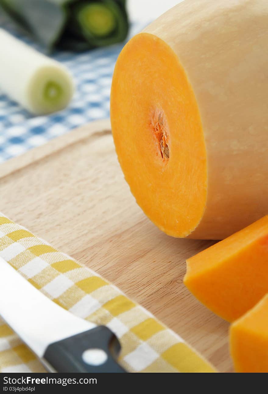 Cut pumpkin on wooden board on checked background