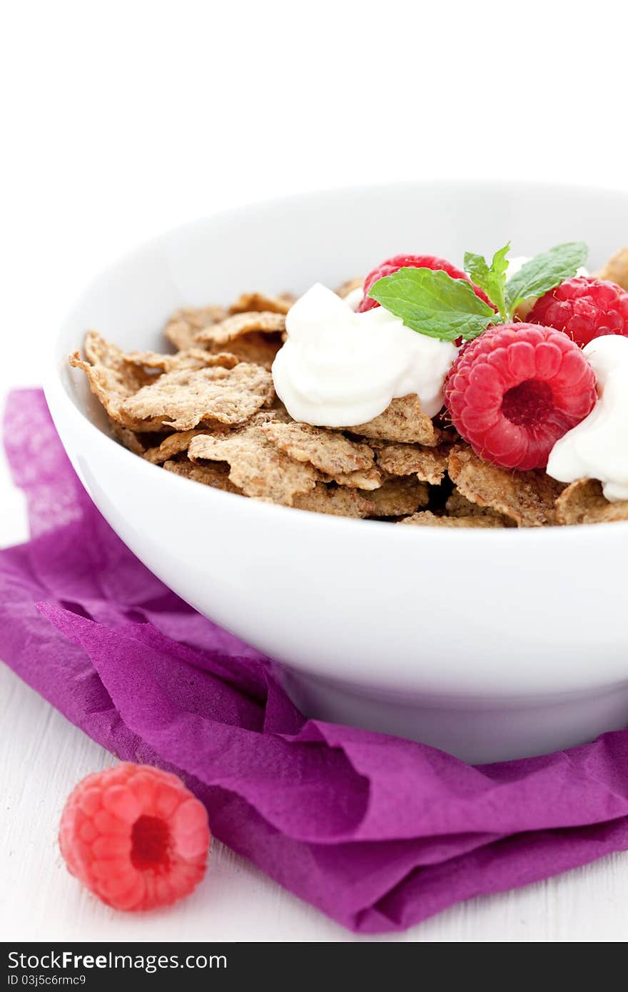 Fresh whole wheat flakes and raspberries in bowl