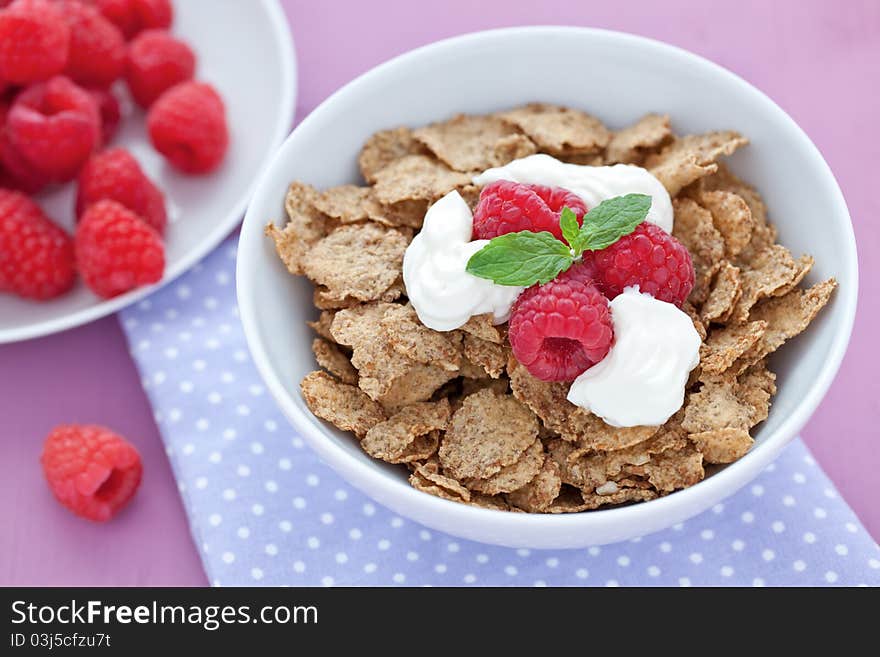 Fresh whole wheat flakes and raspberries in bowl