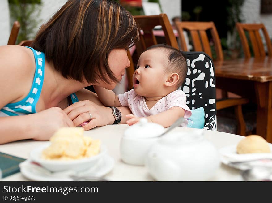 Mother and child at the dining table, with kissing expressions