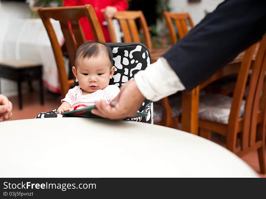 7 month old Asian baby girl, holding the menu, about to order her meal