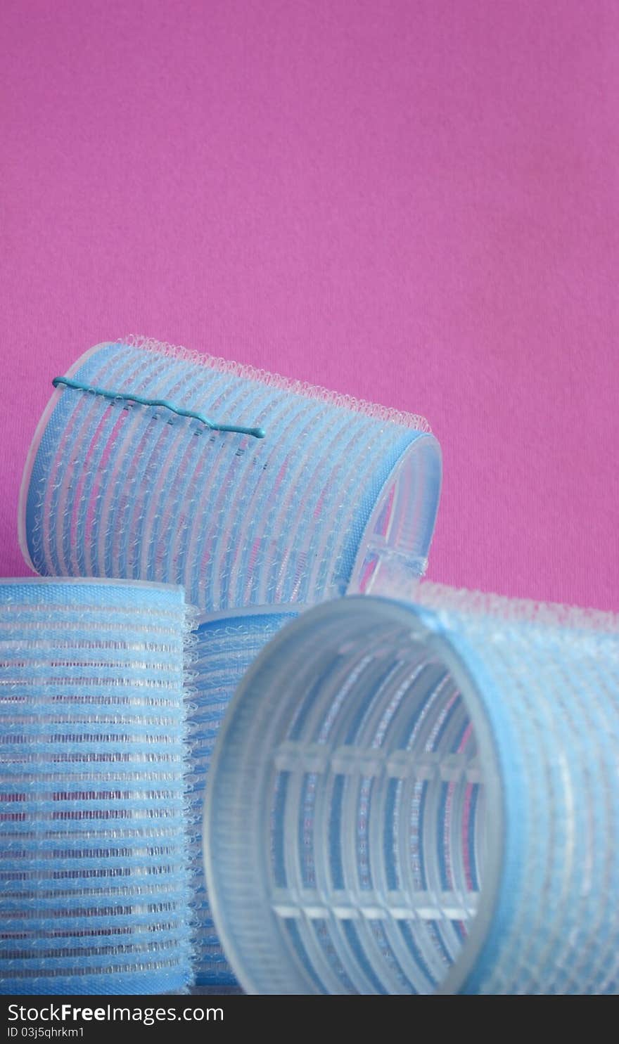 Close-up shot of the blue hair curlers on pink background.