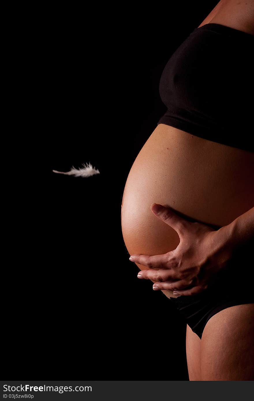 A beautiful close up of a pregnant belly with a feather floating. A beautiful close up of a pregnant belly with a feather floating