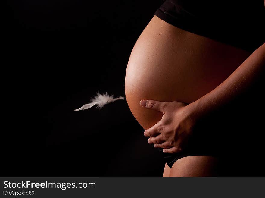 A beautiful close up of a pregnant belly with a feather floating. A beautiful close up of a pregnant belly with a feather floating