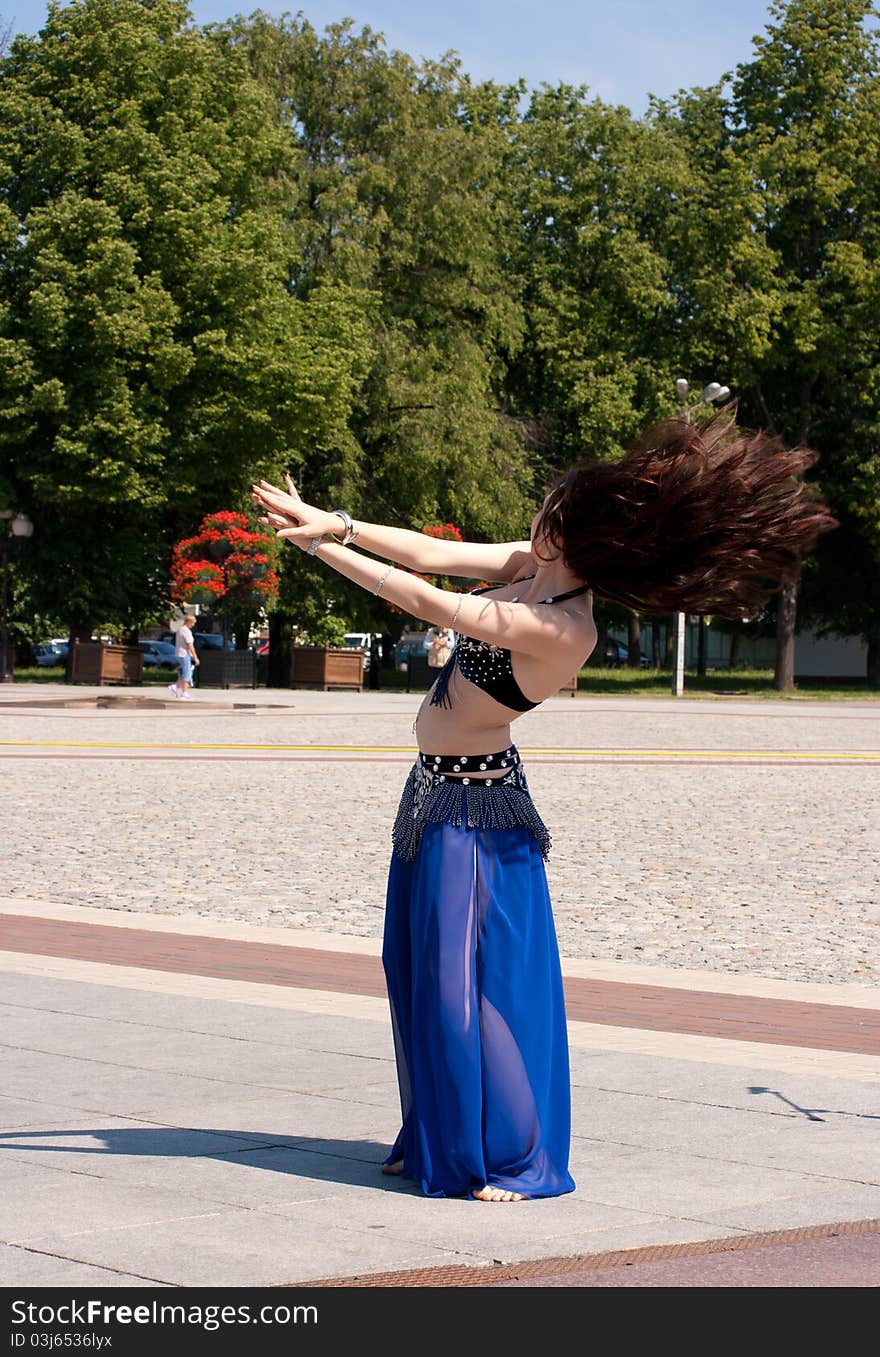 Dancing woman in city square on sunny day in summer