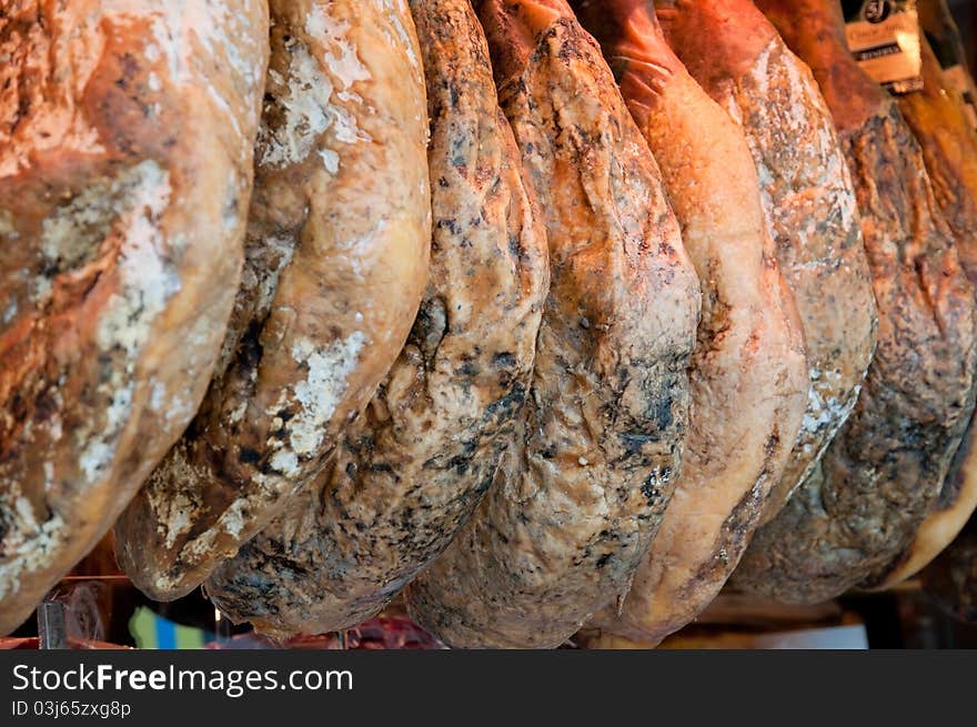 Row of ham hanging in a market place. Selective focus in the centre of the composition. Market place is La Boqueria, close to Las Ramblas in Barcelona.