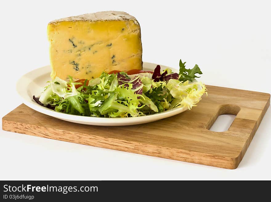 British blue cheese and salad on a white plate on a wooden cheese board