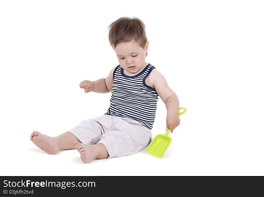 Child playing  with a toy shovel on a white background. Child playing  with a toy shovel on a white background