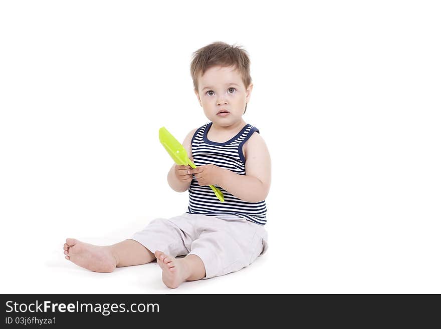 Child playing  with a toy shovel on a white background. Child playing  with a toy shovel on a white background