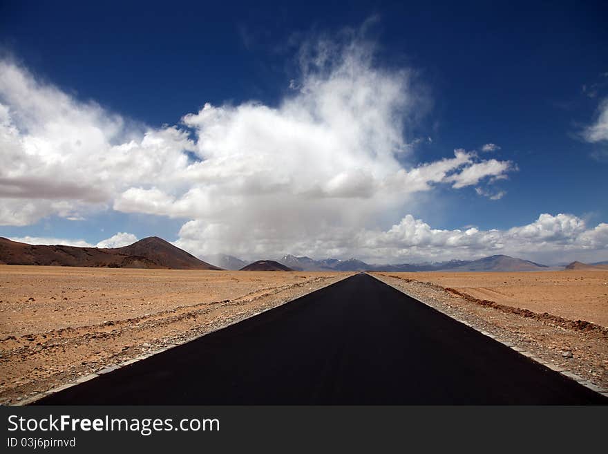 A blacktop road vanishing under beautiful cloudscape. A blacktop road vanishing under beautiful cloudscape