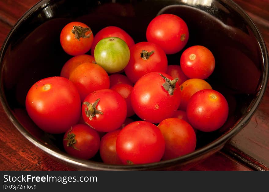 Red tomato in the black bowl